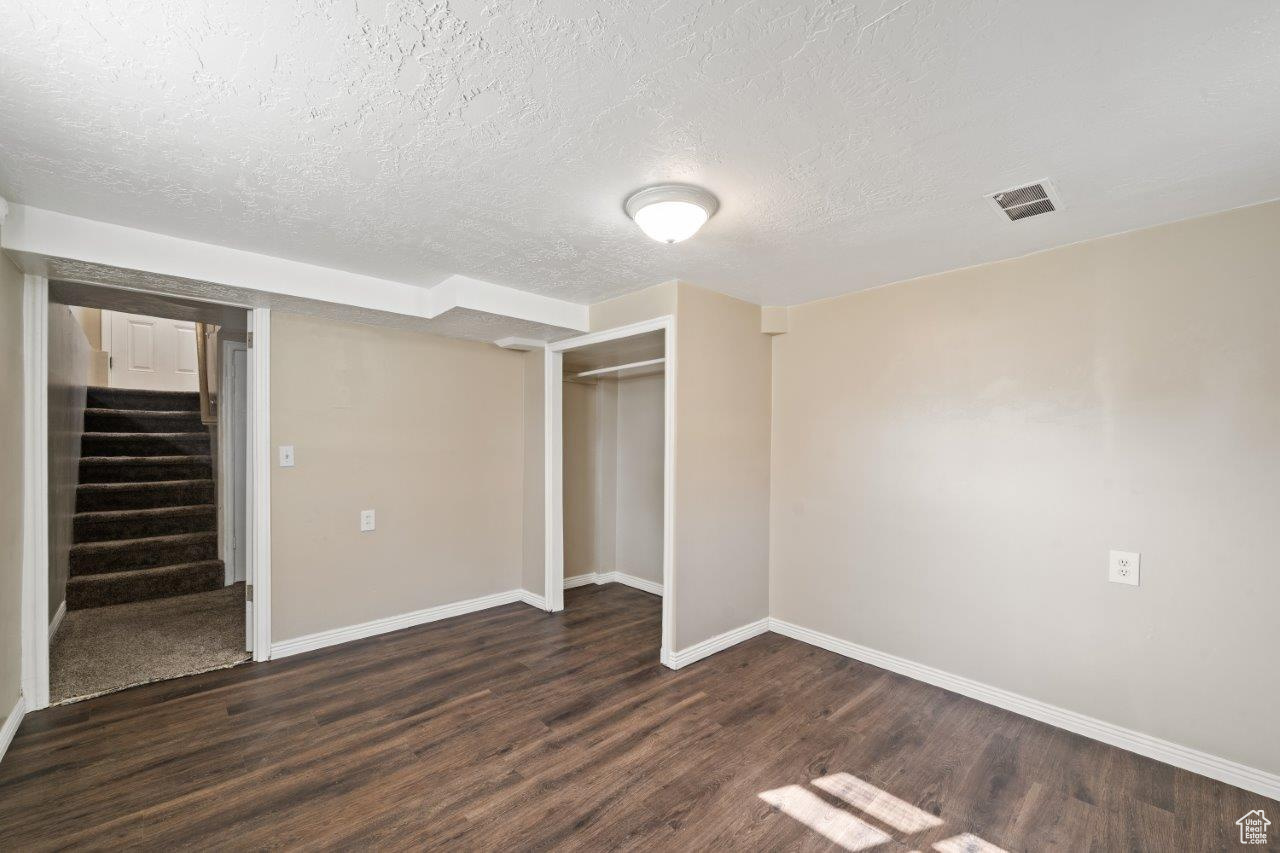 Unfurnished bedroom with dark wood-type flooring, a textured ceiling, and a closet