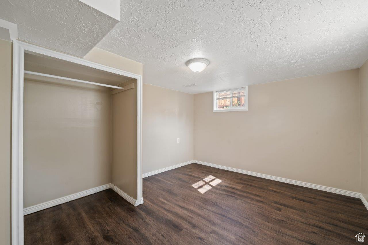 Basement featuring dark wood-type flooring and a textured ceiling