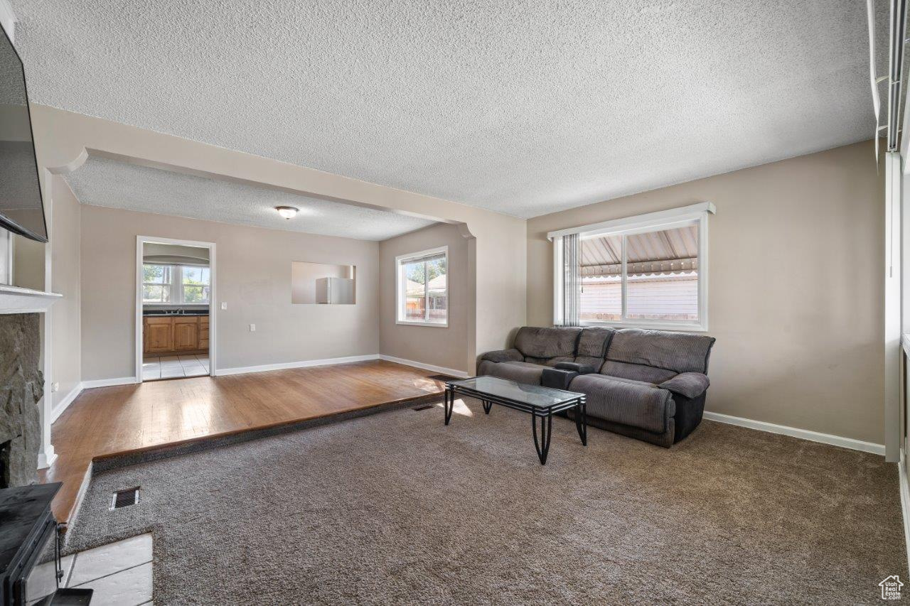 Living room with a fireplace, a textured ceiling, and hardwood / wood-style flooring