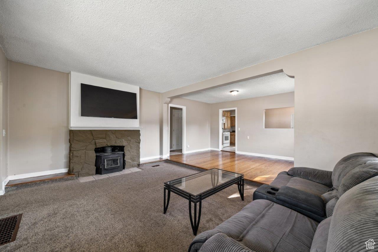 Living room featuring a fireplace, a textured ceiling, and hardwood / wood-style floors