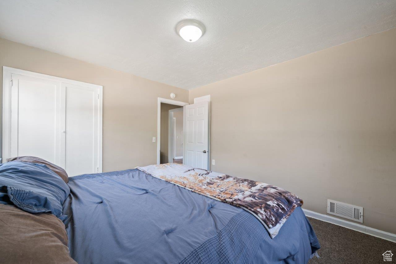 Bedroom featuring dark carpet and a textured ceiling