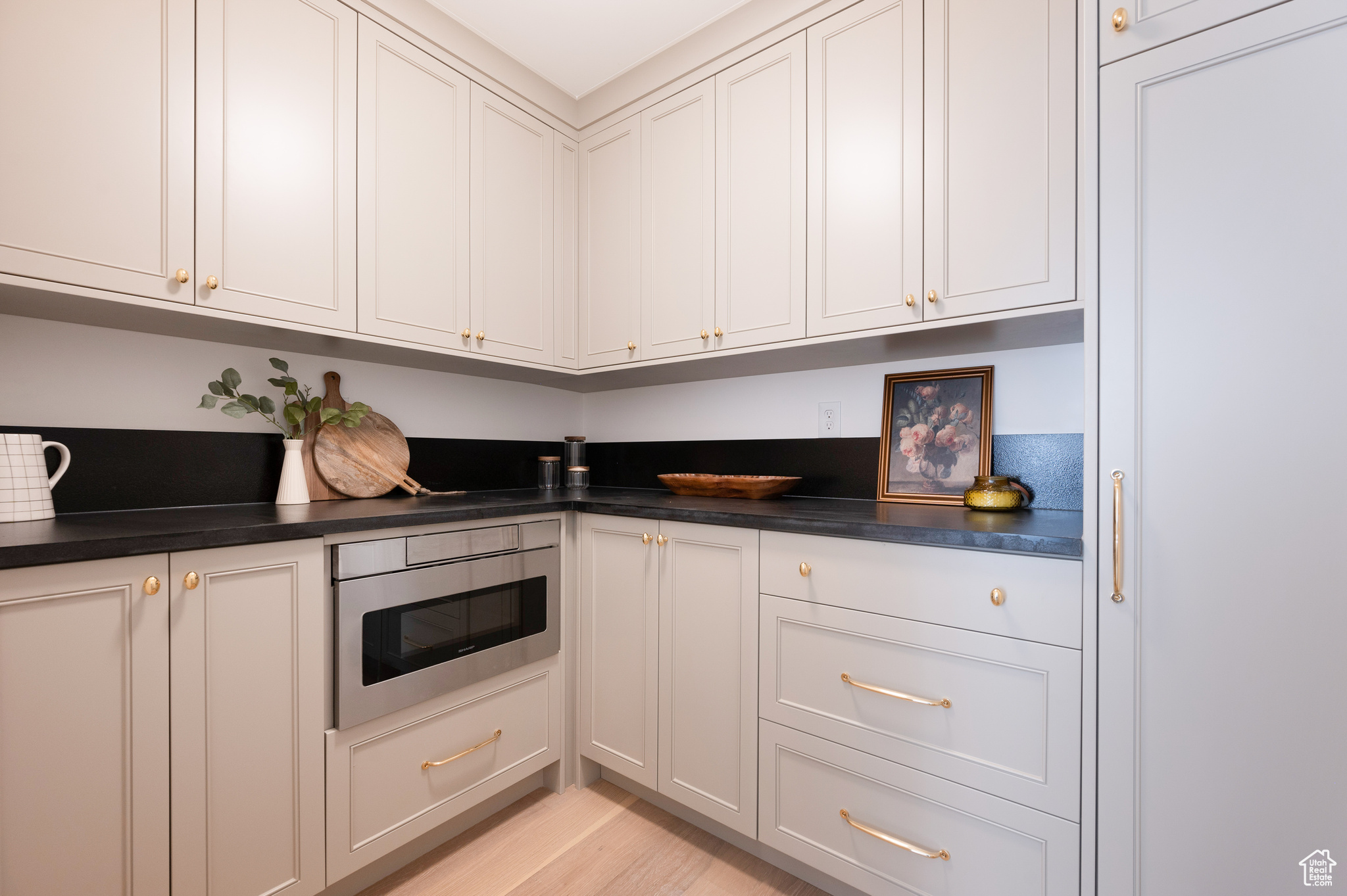 Kitchen with light wood-type flooring, stainless steel oven, and white cabinets