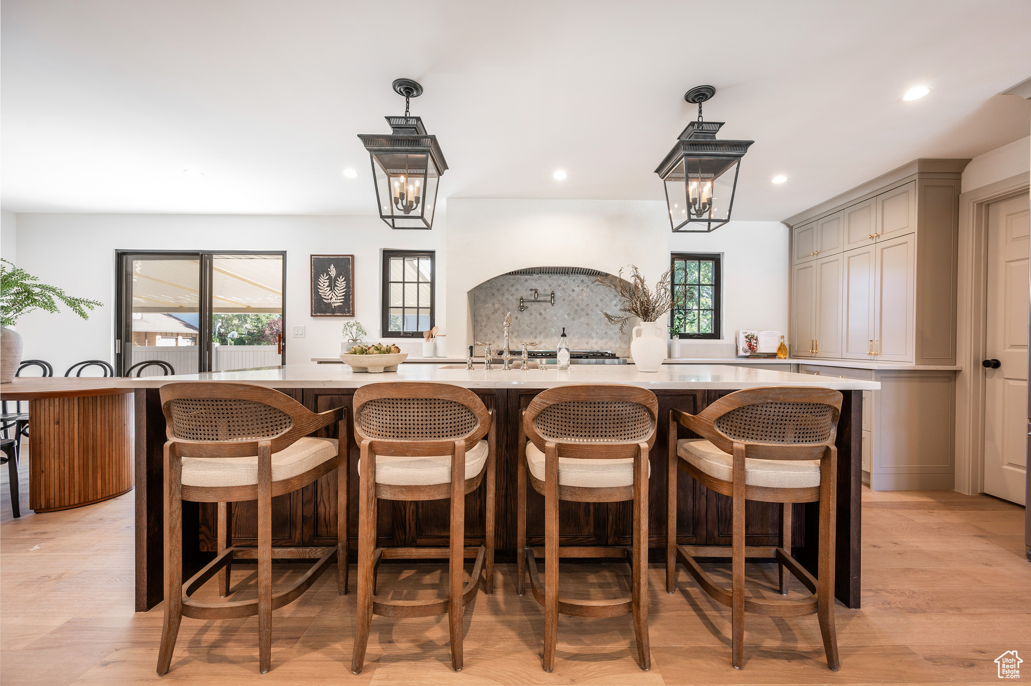 Bar featuring hanging light fixtures, gray cabinetry, backsplash, a notable chandelier, and light hardwood / wood-style floors