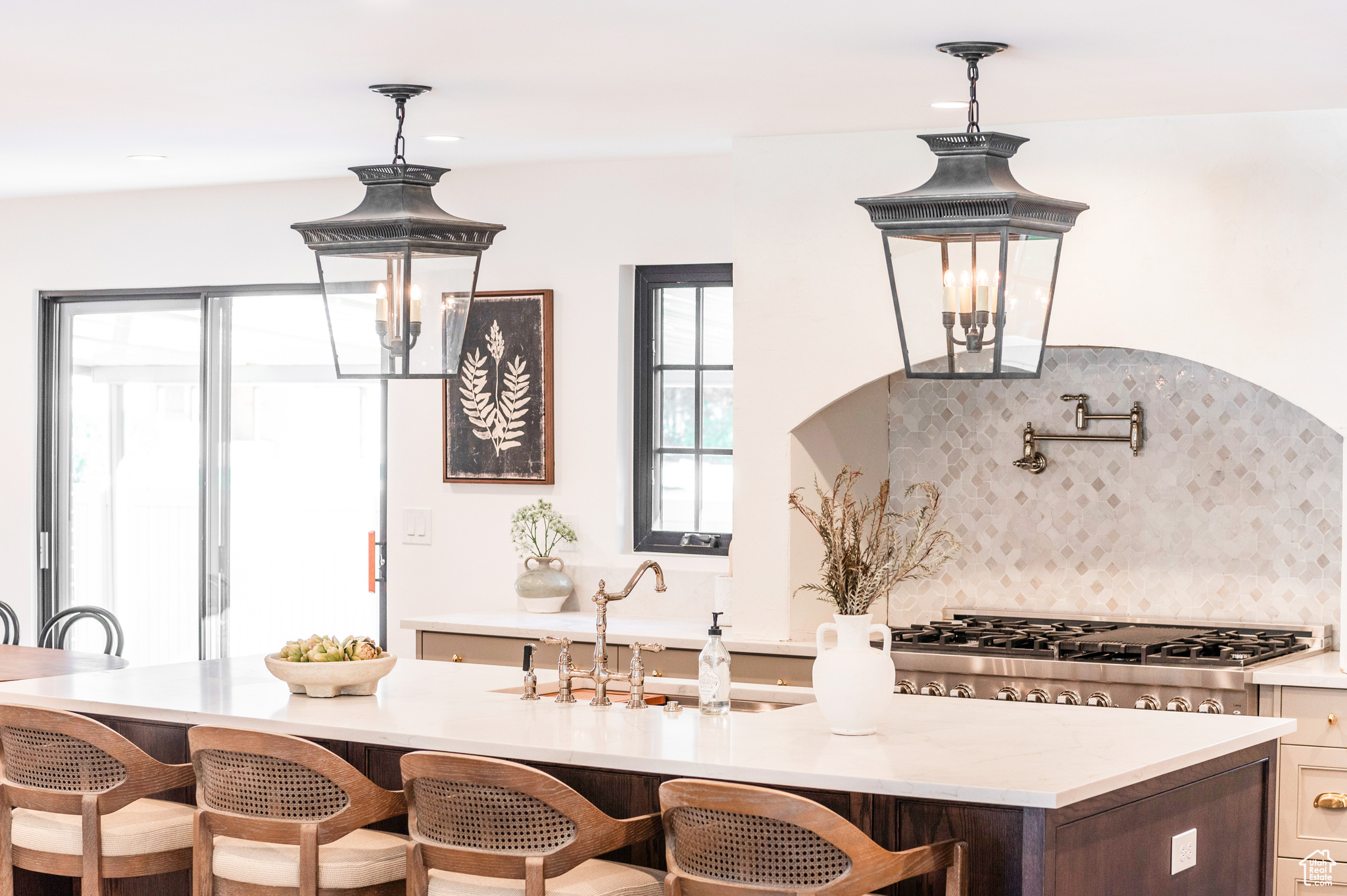 Kitchen with pendant lighting, sink, backsplash, stainless steel gas stovetop, and a breakfast bar