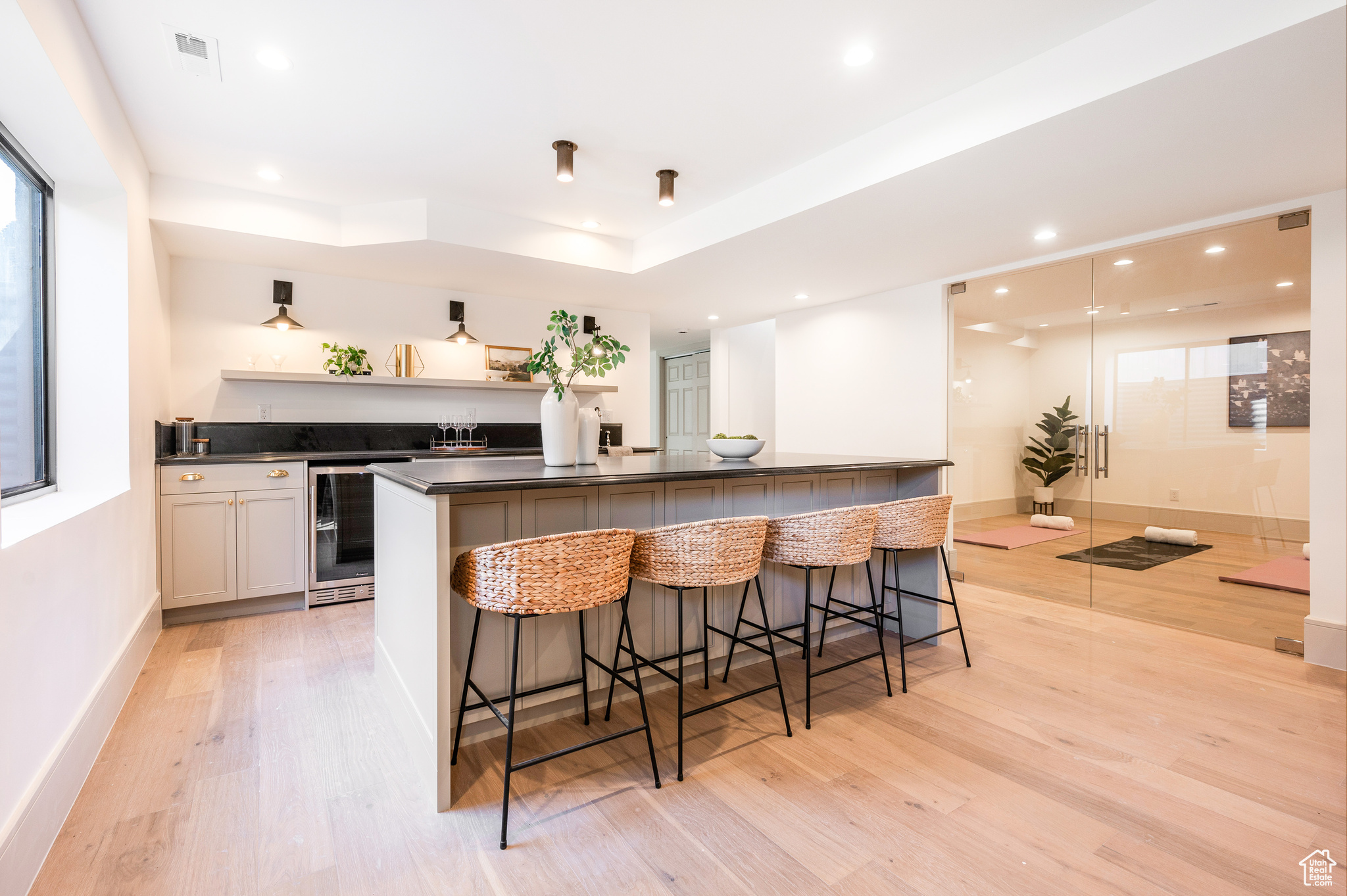 Kitchen featuring white cabinets, a raised ceiling, a breakfast bar area, beverage cooler, and light hardwood / wood-style flooring