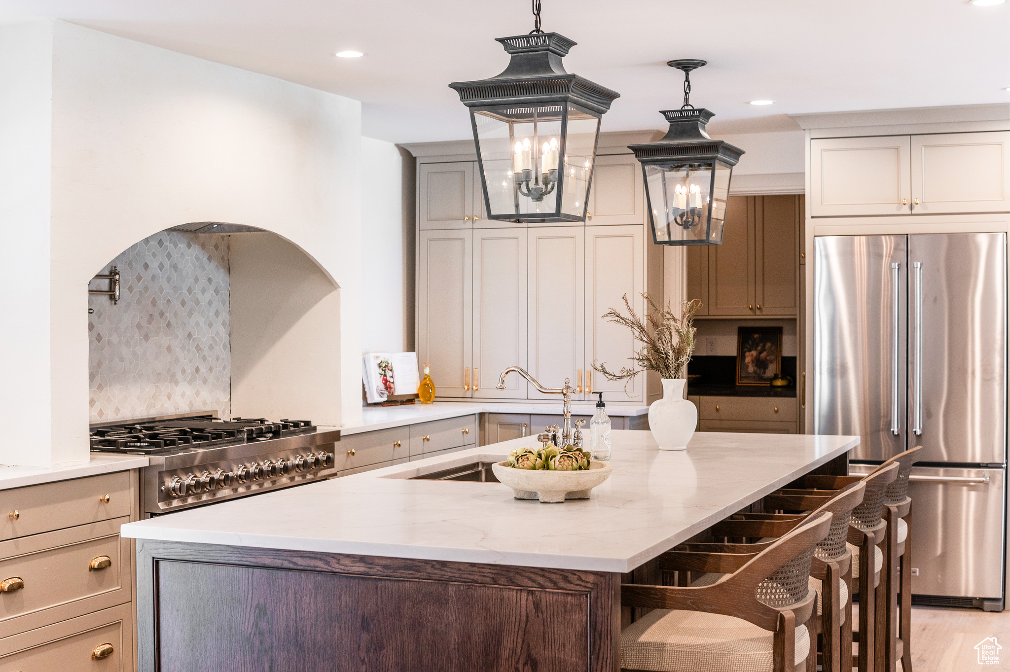 Kitchen featuring appliances with stainless steel finishes, hanging light fixtures, backsplash, light wood-type flooring, and a kitchen bar