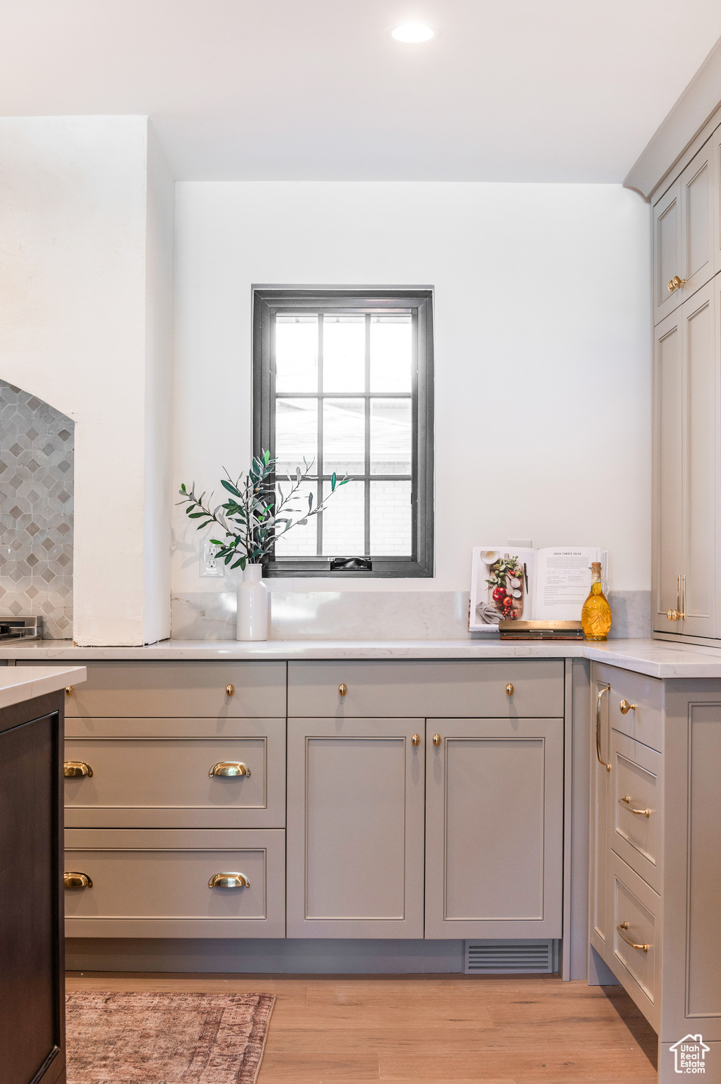 Kitchen featuring gray cabinets, decorative backsplash, and light wood-type flooring