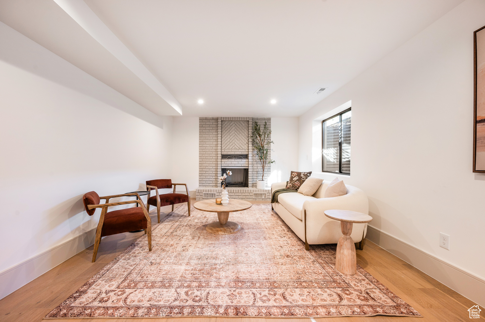 Living room with a brick fireplace and hardwood / wood-style flooring