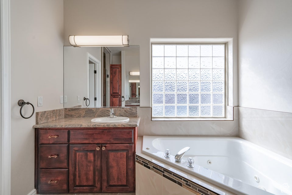 Bathroom featuring tiled tub and vanity