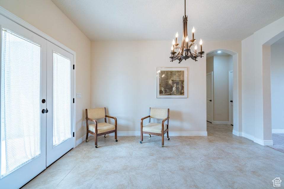 Living area with a healthy amount of sunlight, an inviting chandelier, and french doors