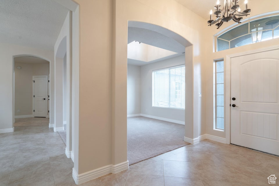 Entryway with light tile patterned floors, a chandelier, and a textured ceiling