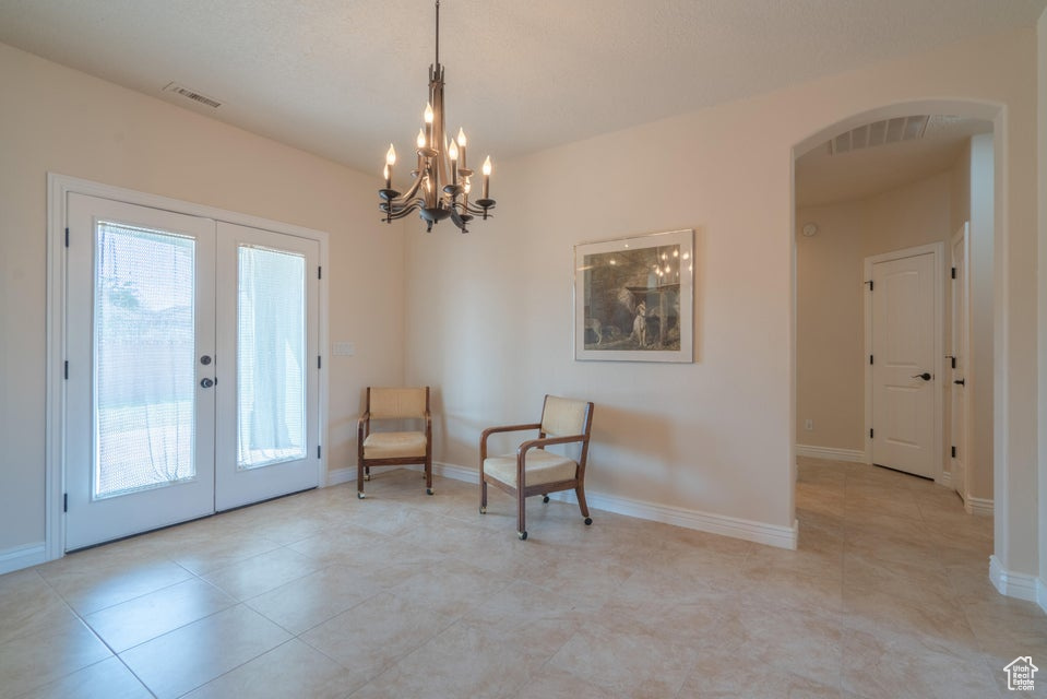 Living area with french doors, a wealth of natural light, light tile patterned floors, and a chandelier