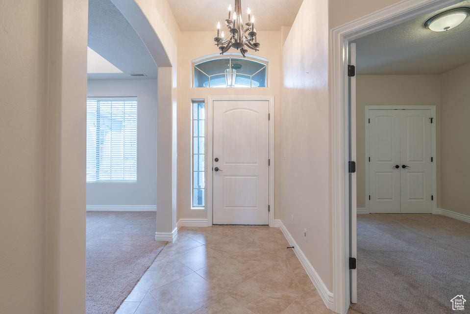 Carpeted entryway with a notable chandelier