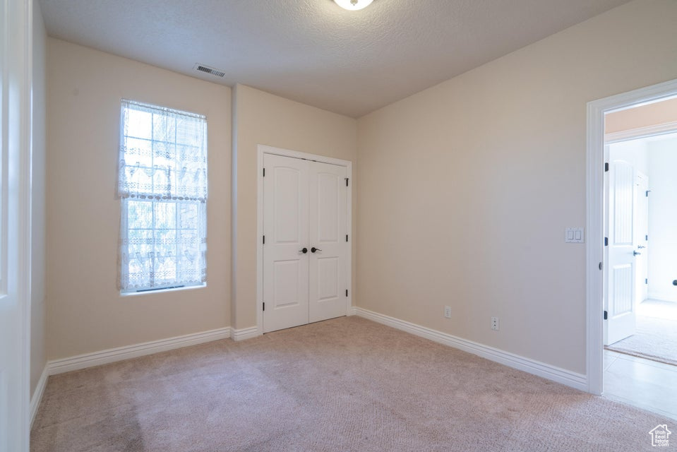 Unfurnished room with a textured ceiling and light colored carpet