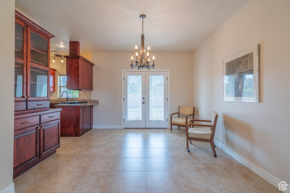 Interior space featuring a textured ceiling, plenty of natural light, an inviting chandelier, and french doors