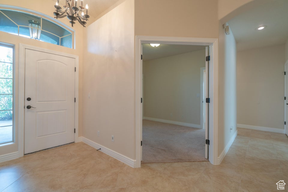 Foyer entrance featuring light carpet and an inviting chandelier