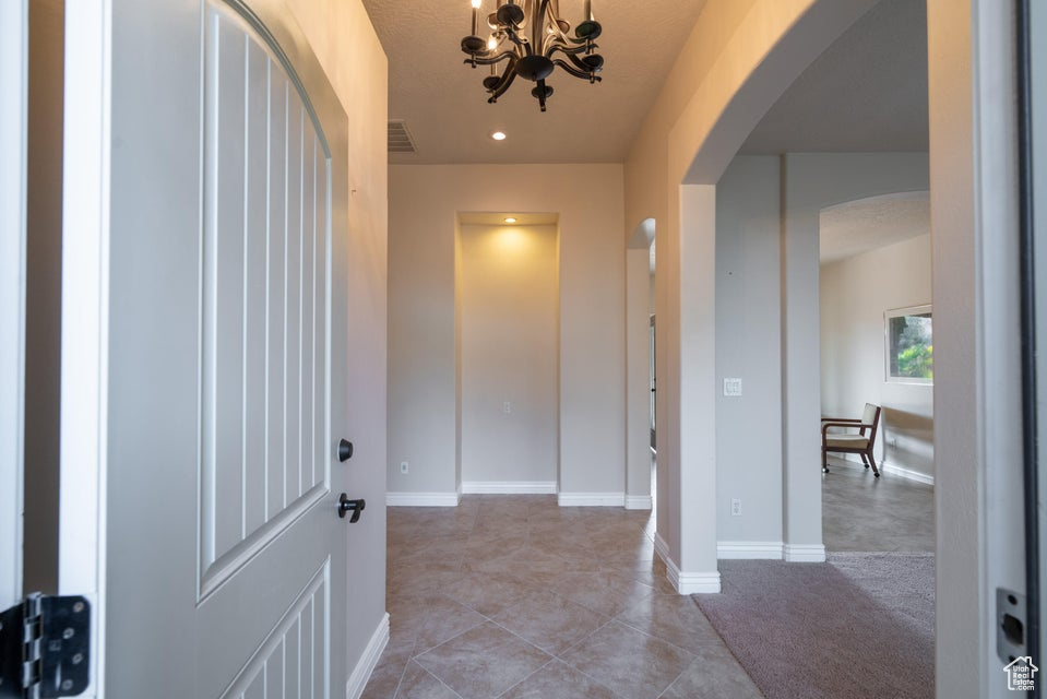 Foyer with a chandelier and light colored carpet