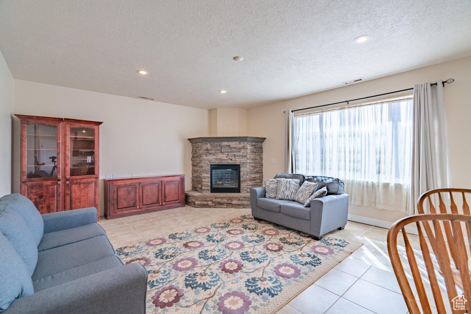 Tiled living room with a fireplace and a textured ceiling