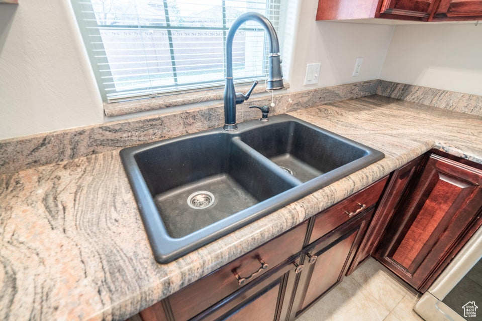 Interior space featuring light tile patterned floors, light stone counters, and sink