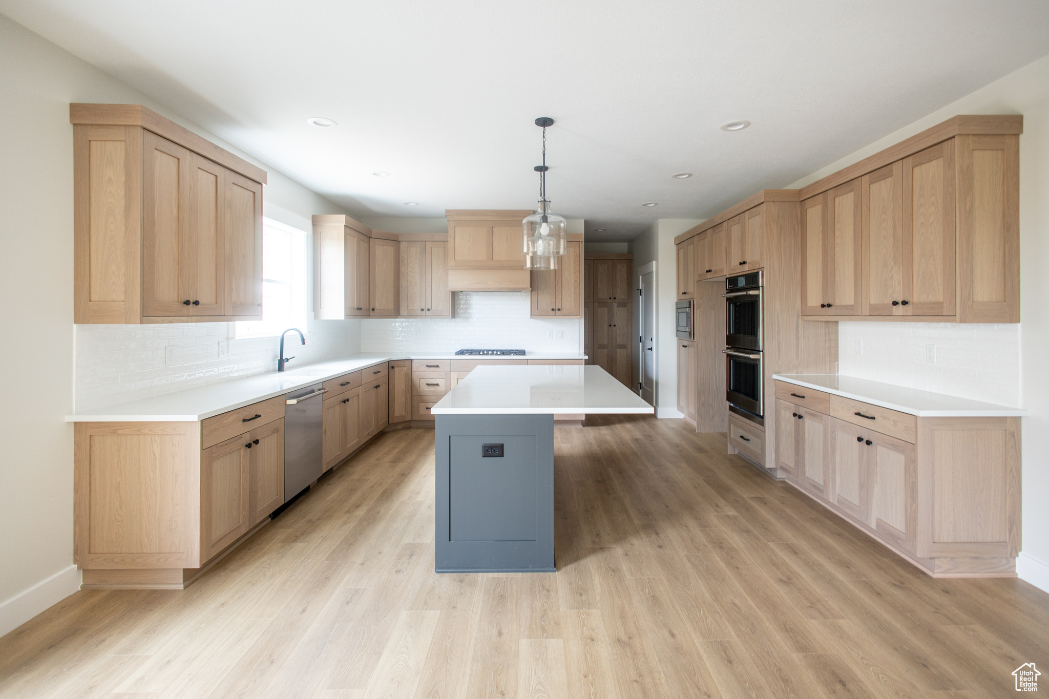 Kitchen featuring custom cabinetry, decorative pendant lights, a kitchen island, tile backsplash and high end GE Cafe Appliances