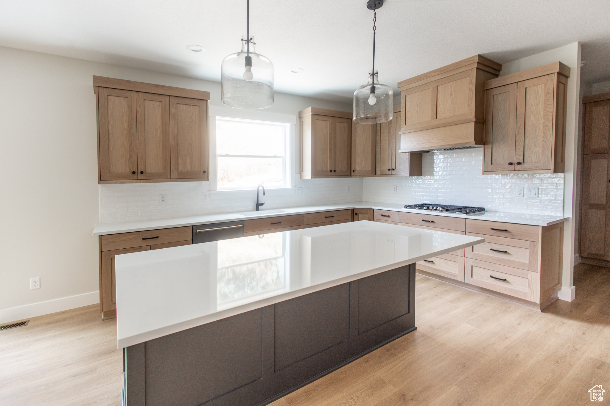 Kitchen featuring quartz countertops, custom wood range hood and window over the sink to a private backyard