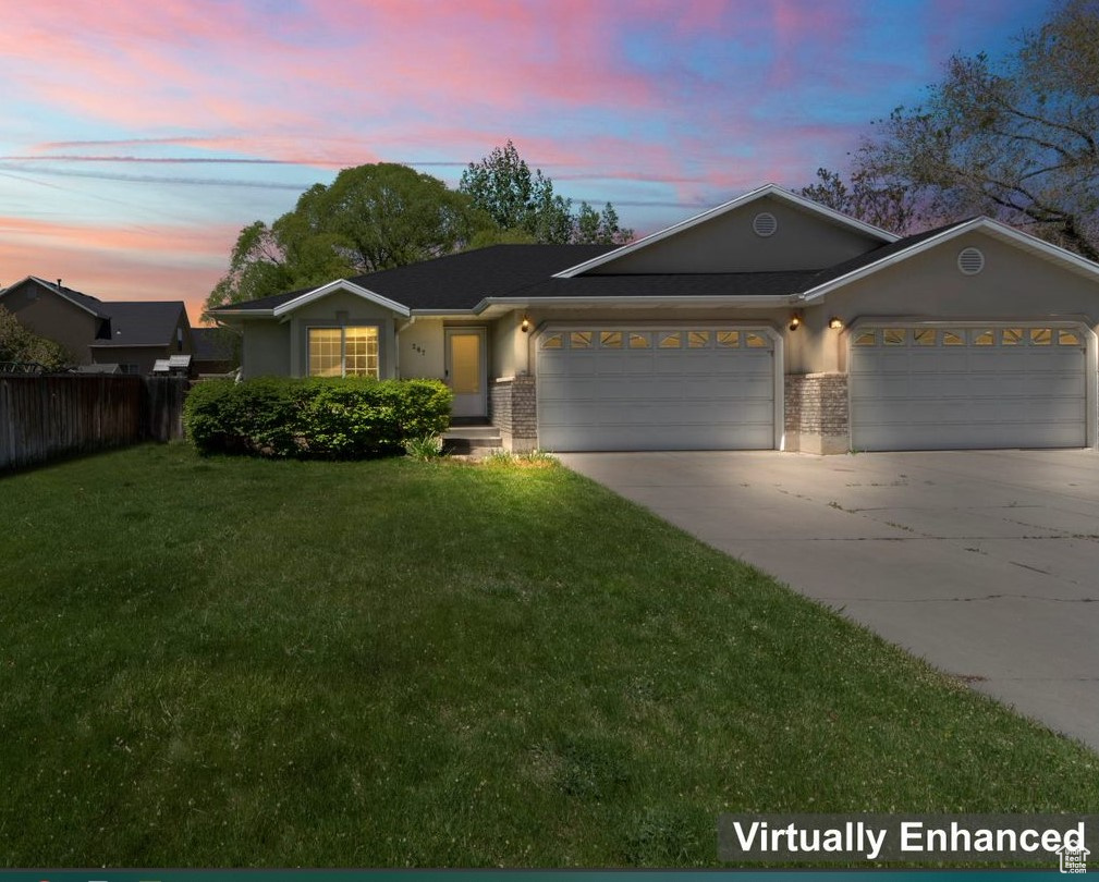 Ranch-style house featuring a garage and a lawn