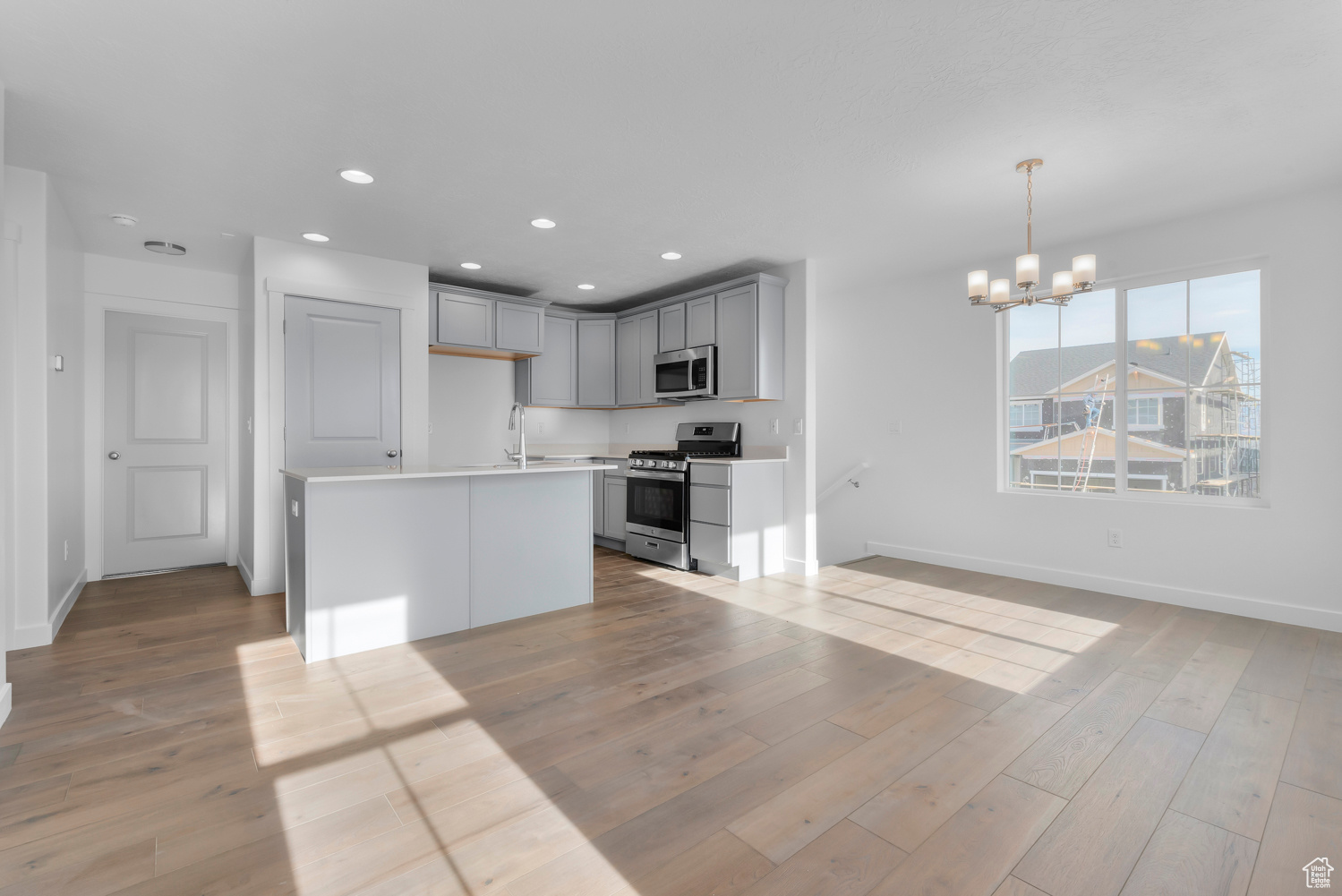 Kitchen with a chandelier, decorative light fixtures, gray cabinets, a kitchen island, and appliances with stainless steel finishes