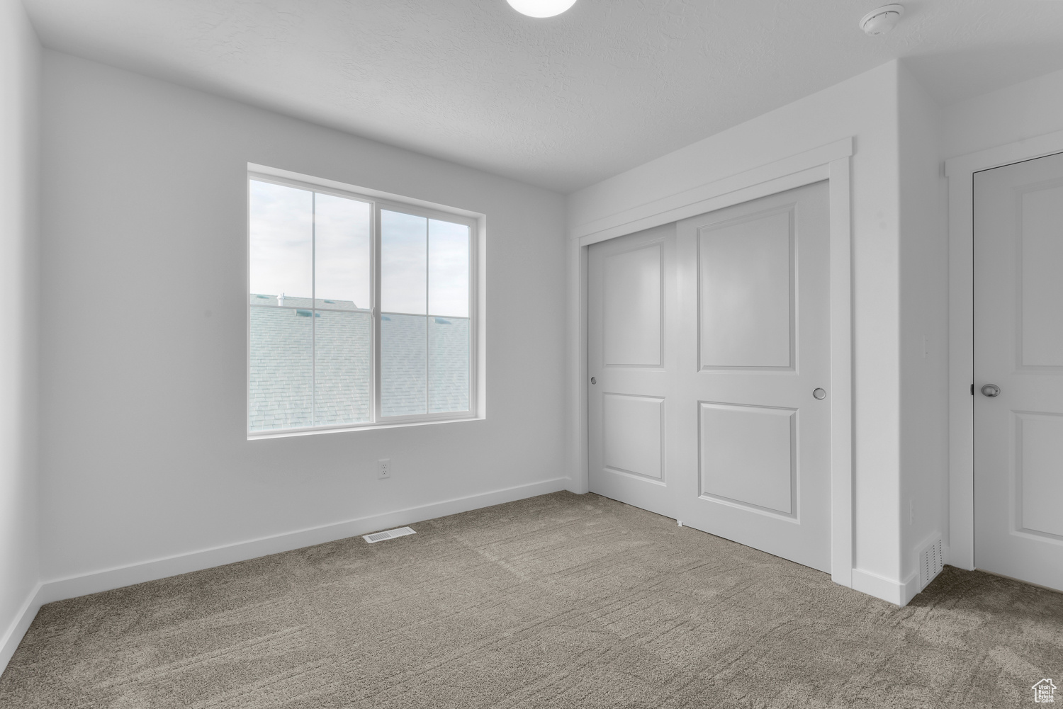 Unfurnished bedroom featuring light colored carpet and a closet