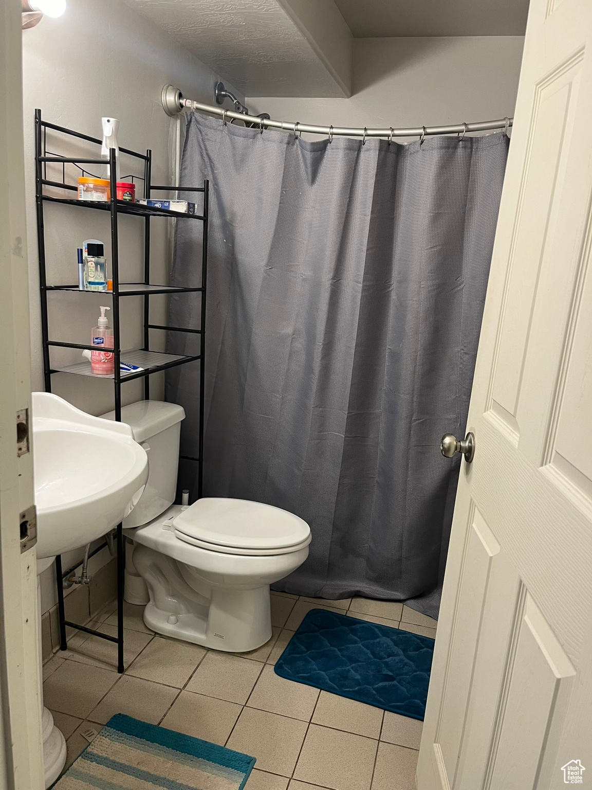 Bathroom featuring toilet, a shower with curtain, and tile patterned flooring