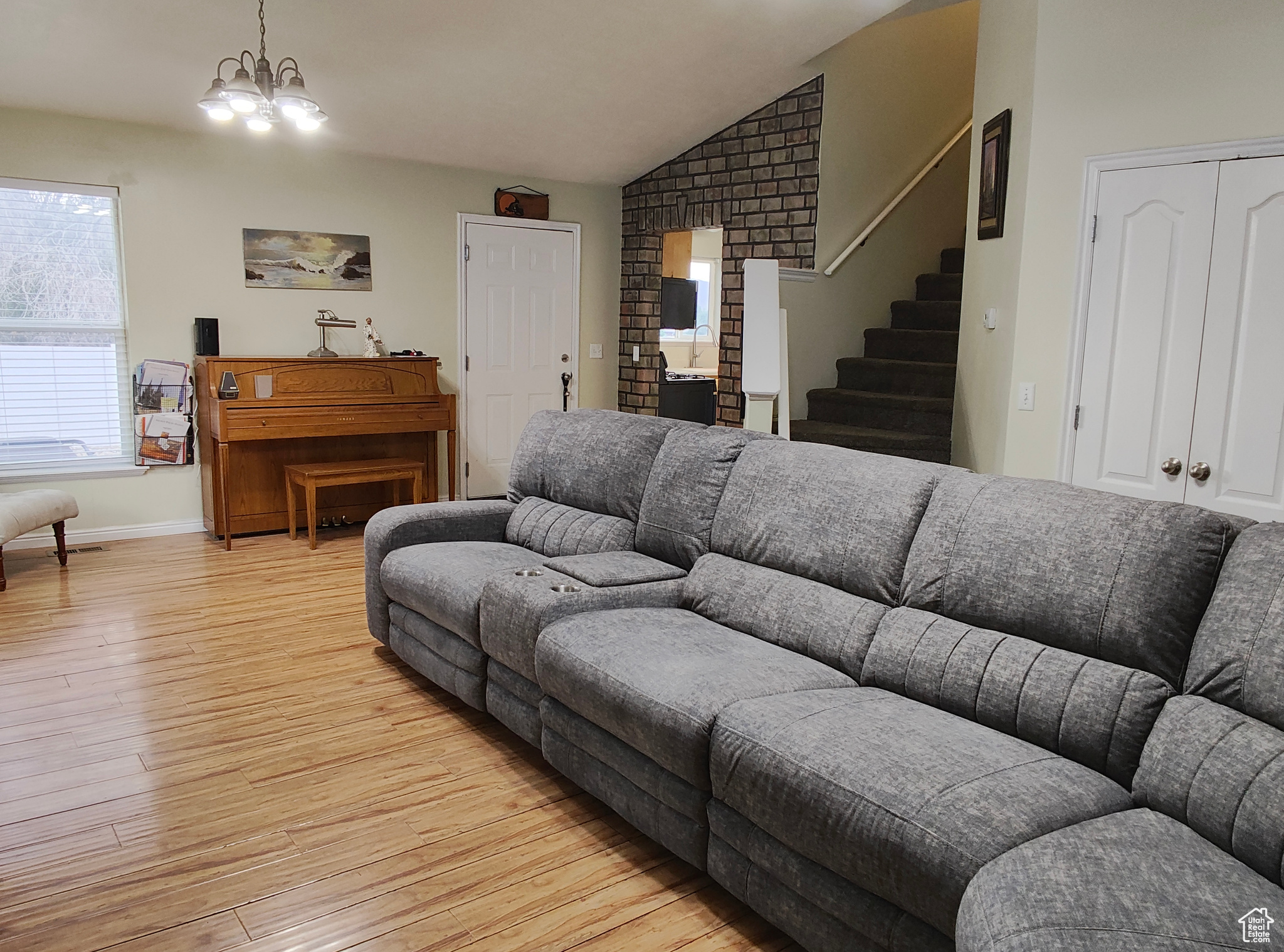 Living room with vaulted ceiling, light hardwood / wood-style floors, and a chandelier