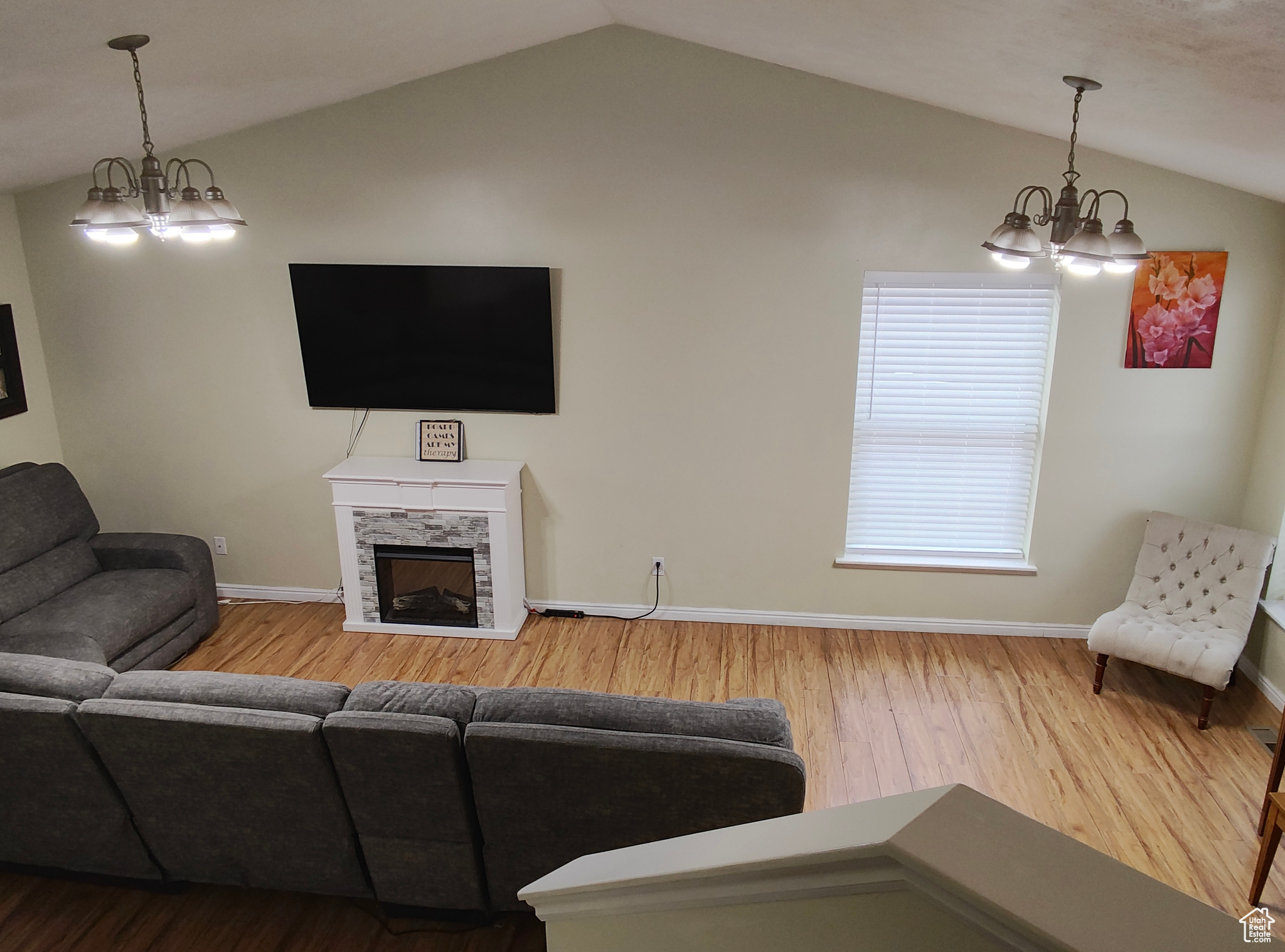 Living room featuring a notable chandelier, a tile fireplace, vaulted ceiling, and hardwood / wood-style flooring