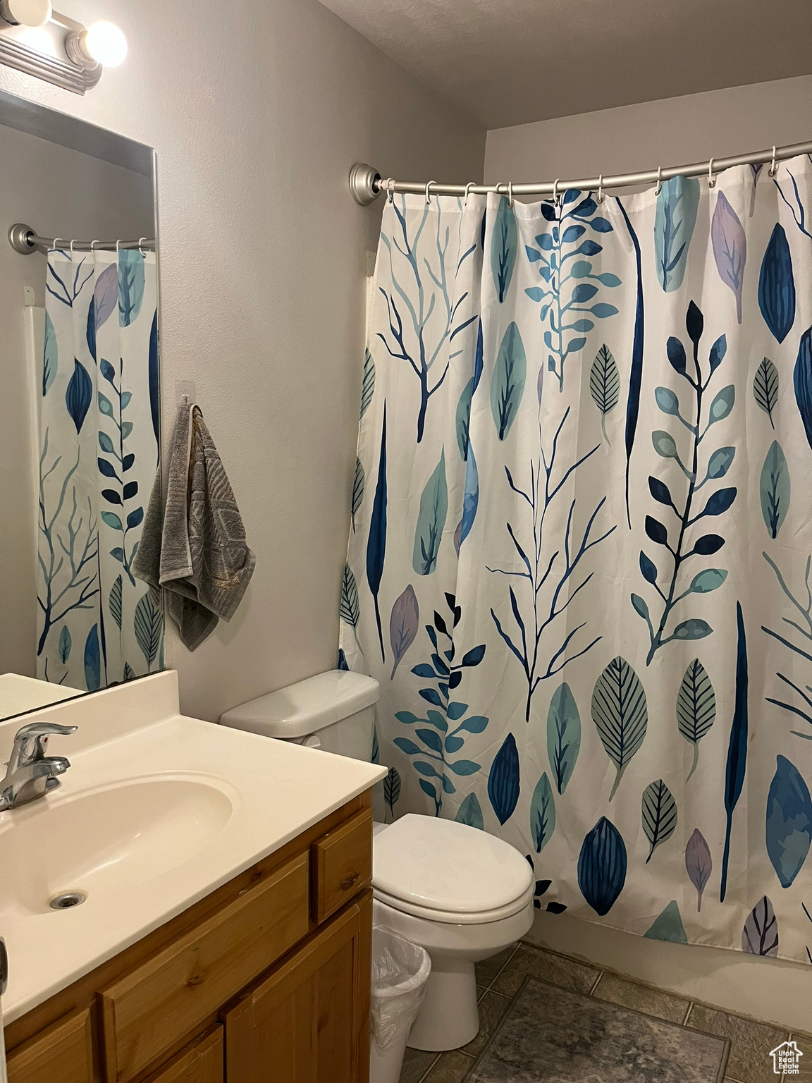 Bathroom with curtained shower, tile patterned flooring, toilet, and vanity