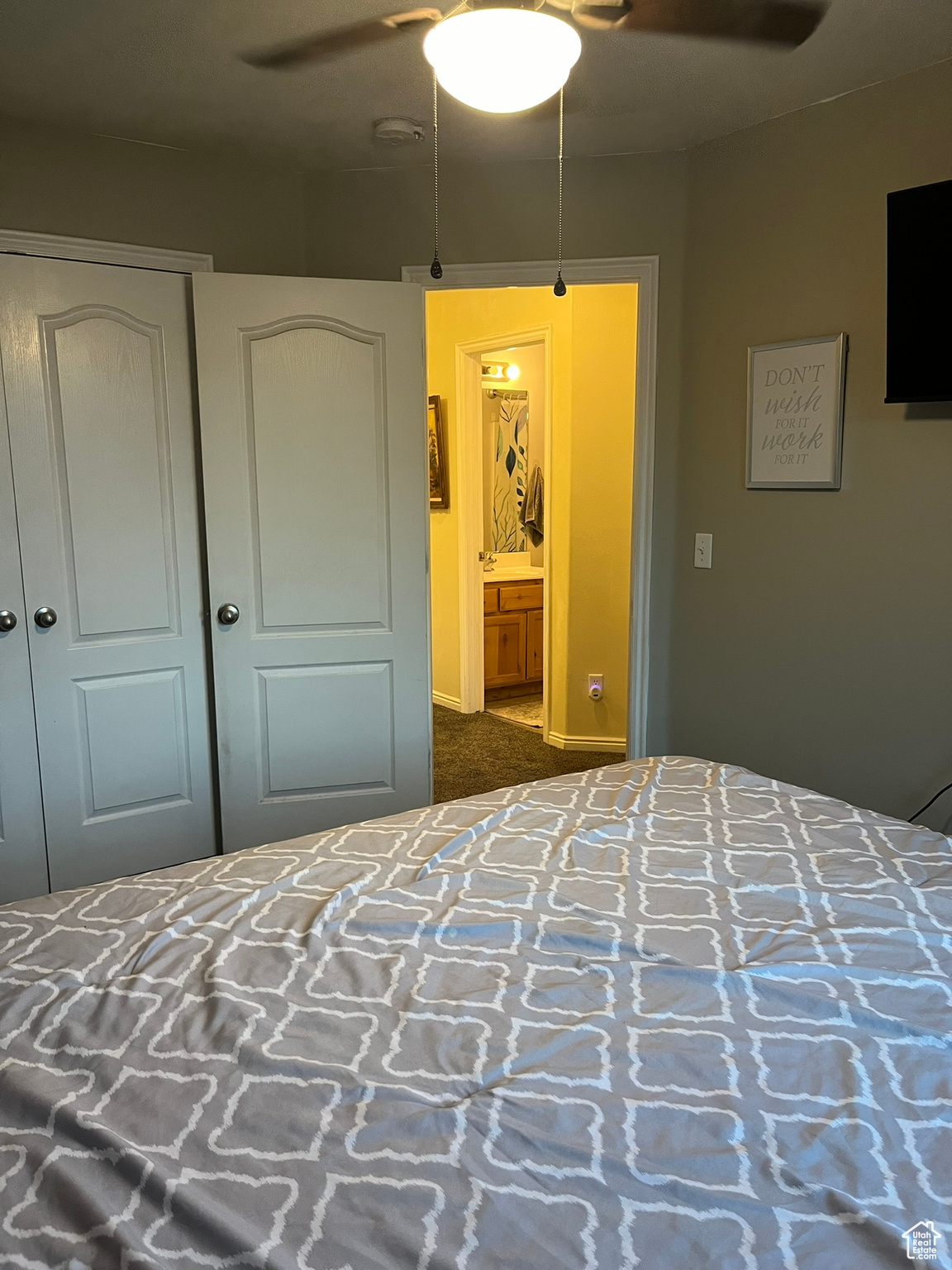 Bedroom with ensuite bath, dark carpet, and ceiling fan