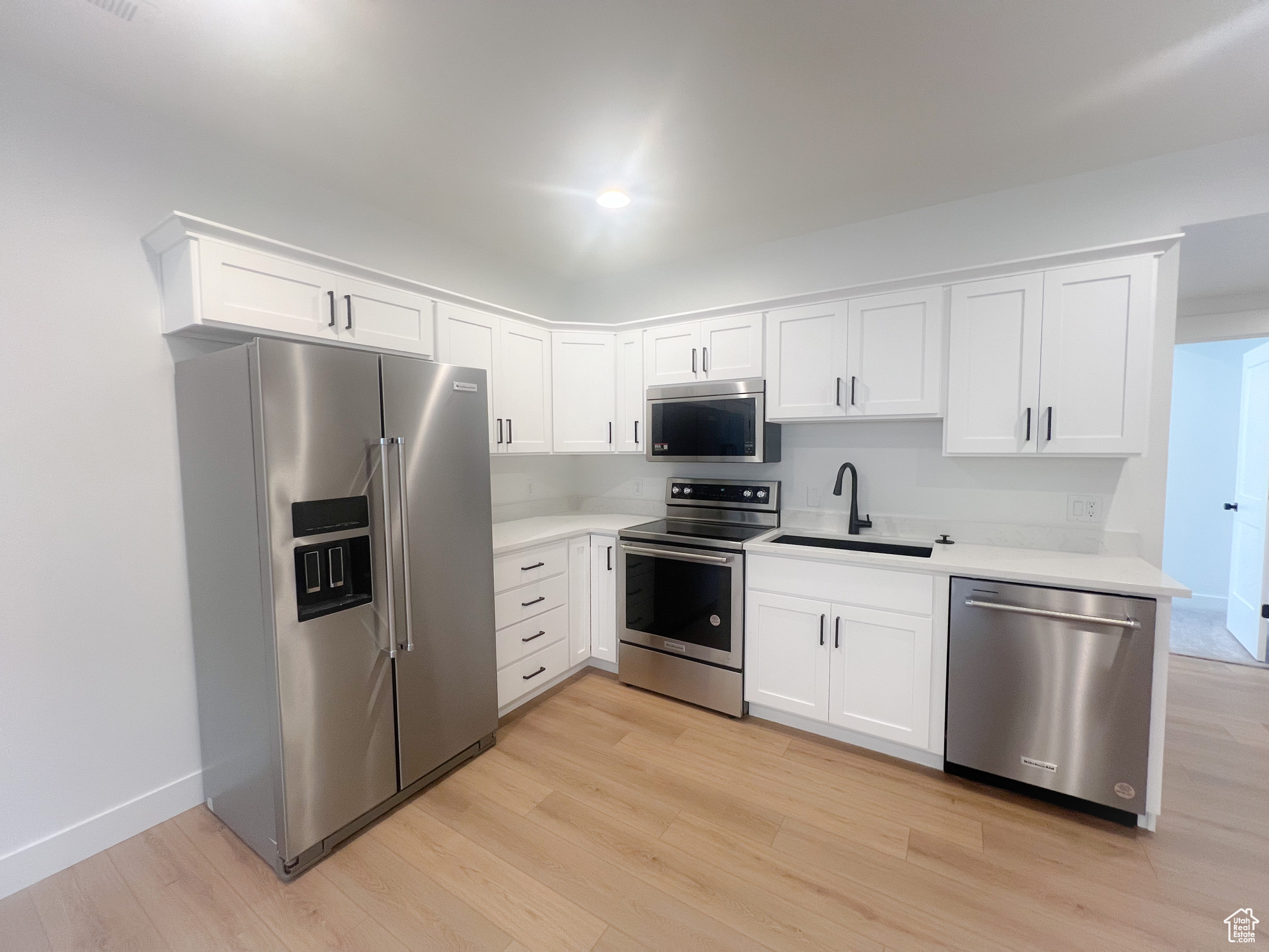 Kitchen featuring white cabinetry, light hardwood / wood-style flooring, stainless steel appliances, and sink