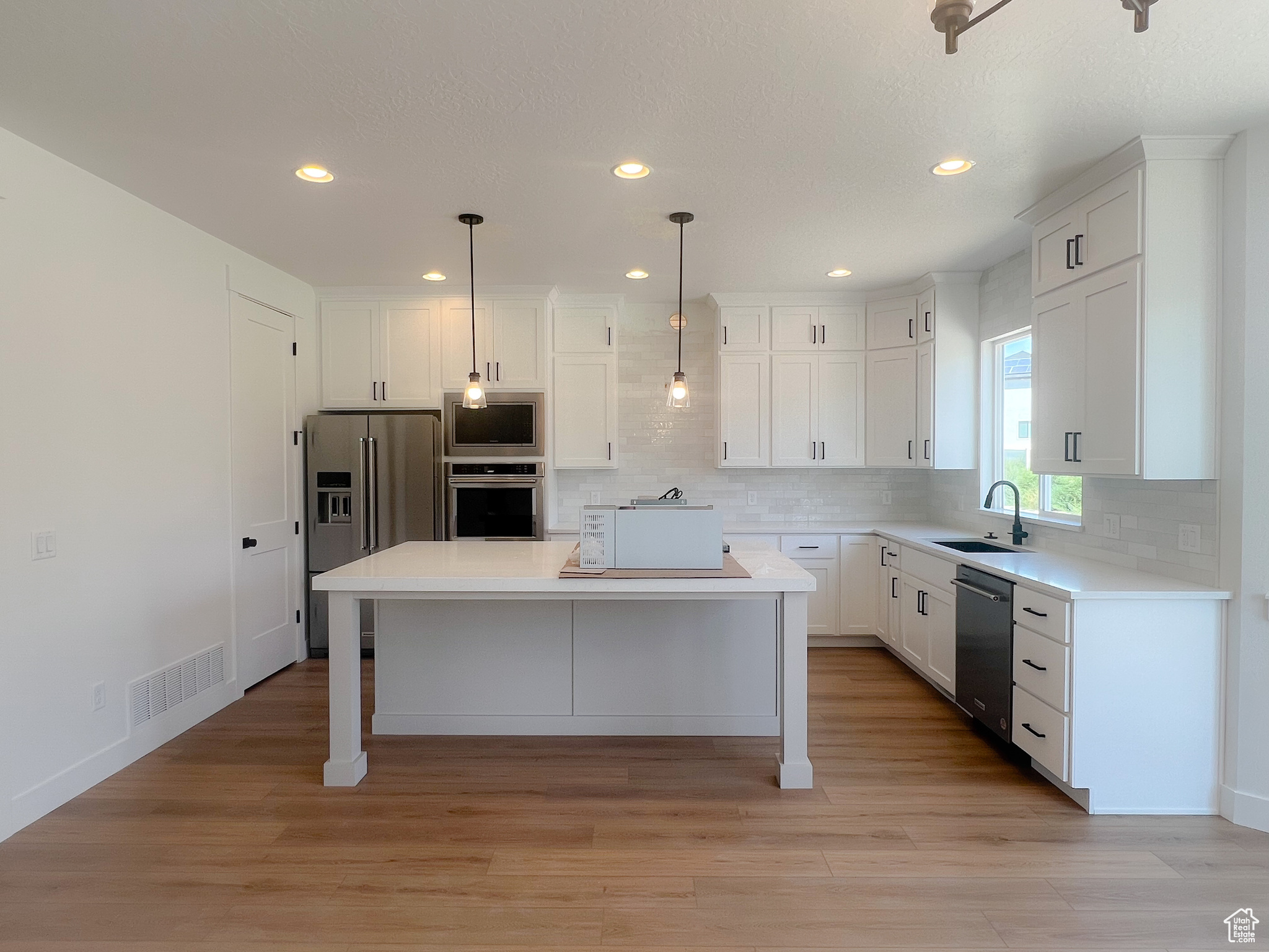 Kitchen featuring light hardwood / wood-style flooring, appliances with stainless steel finishes, sink, a kitchen breakfast bar, and a kitchen island