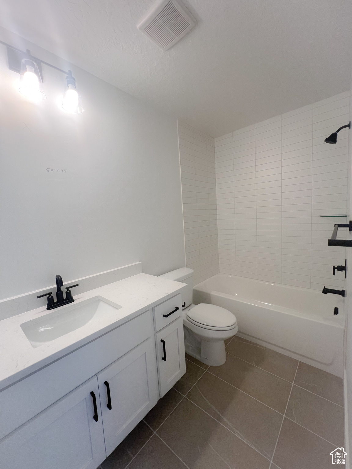 Full bathroom with vanity, toilet, tiled shower / bath combo, and tile patterned floors