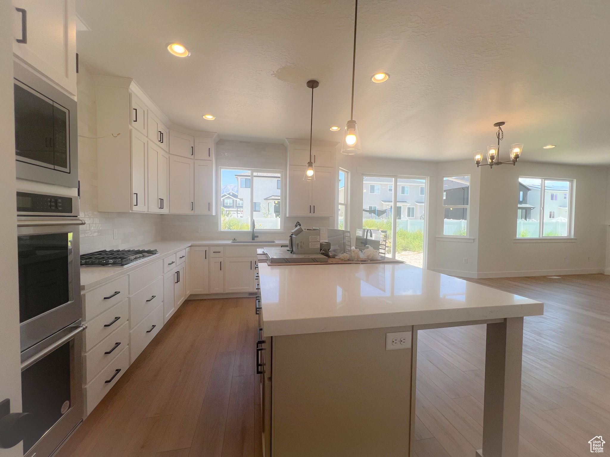 Kitchen with light wood-type flooring, appliances with stainless steel finishes, white cabinetry, and a kitchen island