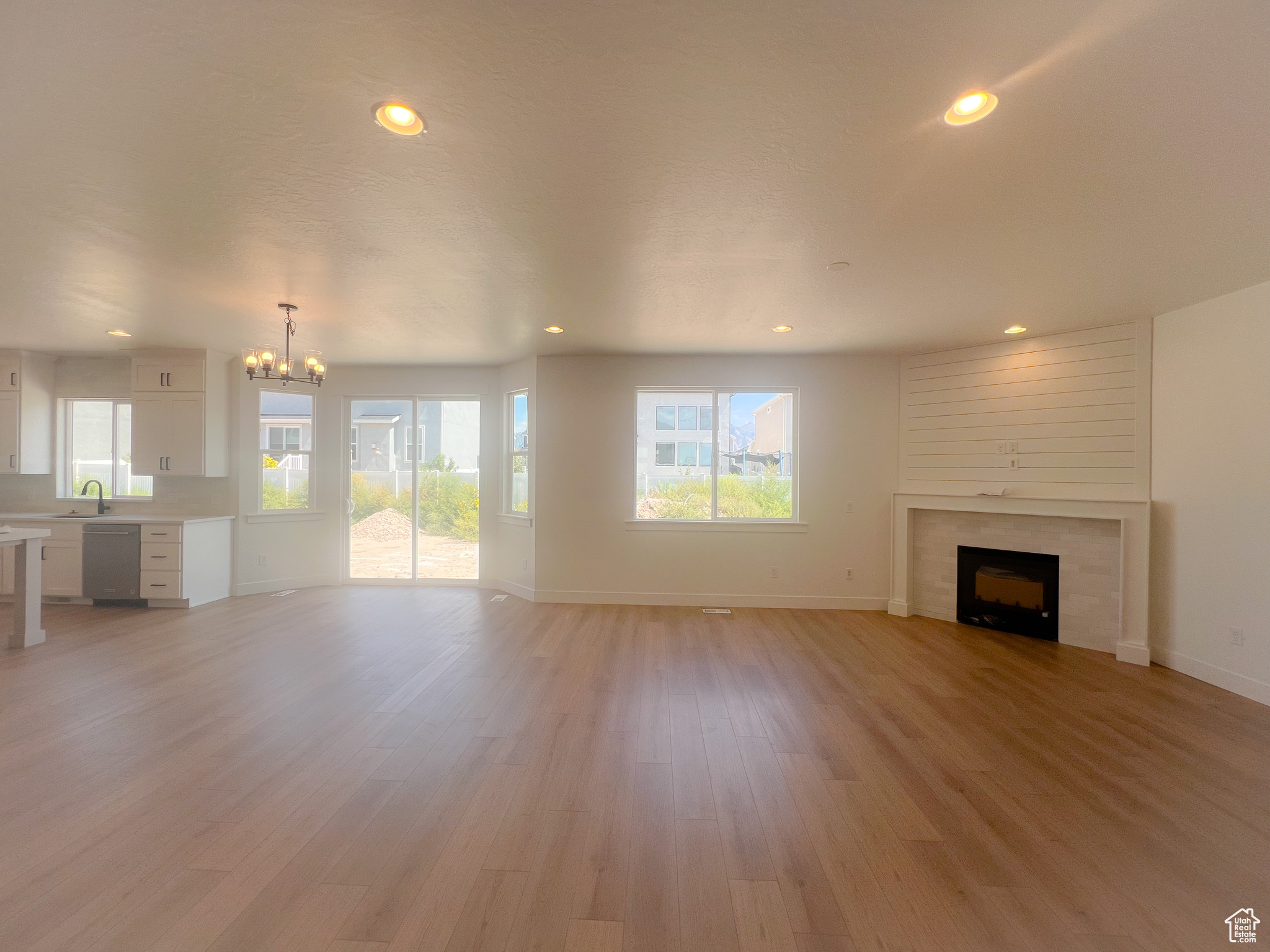 Unfurnished living room with light hardwood / wood-style flooring, a notable chandelier, sink, and a large fireplace