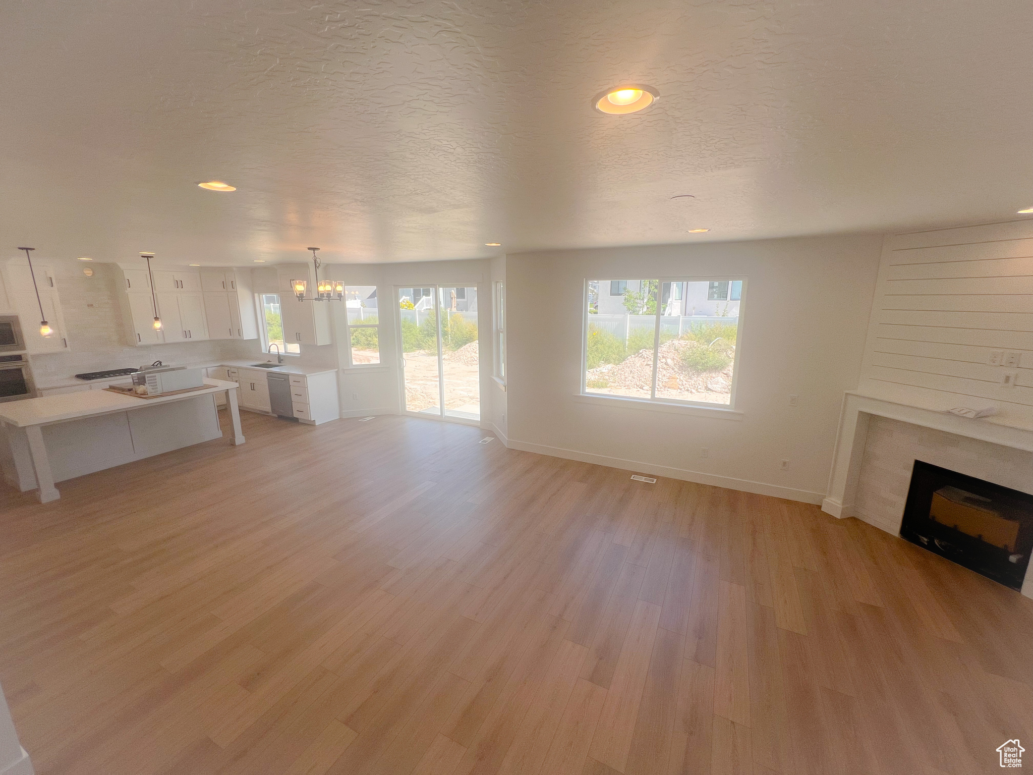 Unfurnished living room with sink, an inviting chandelier, light hardwood / wood-style floors, and a textured ceiling