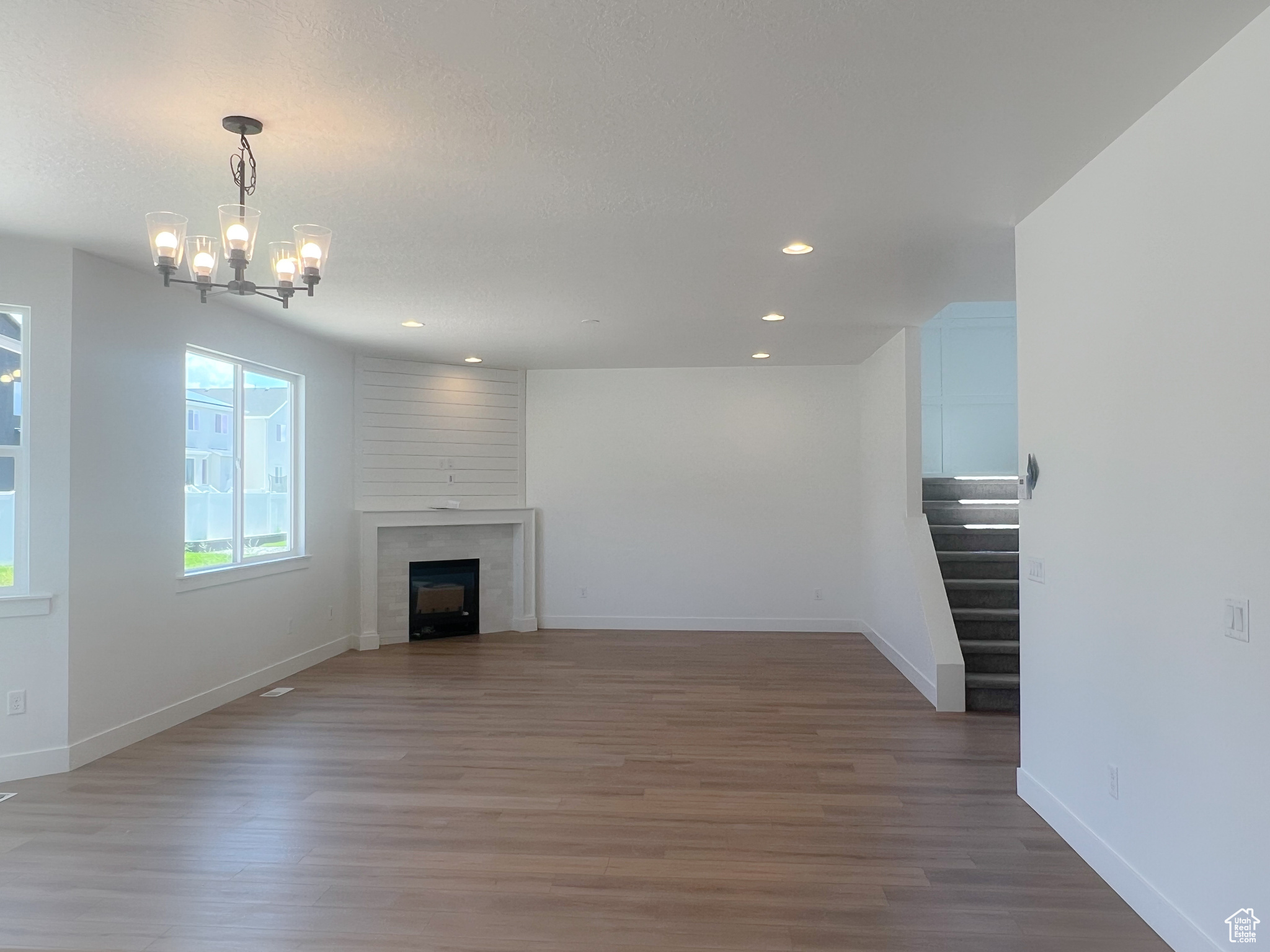 Unfurnished living room with a large fireplace, dark hardwood / wood-style flooring, and a notable chandelier