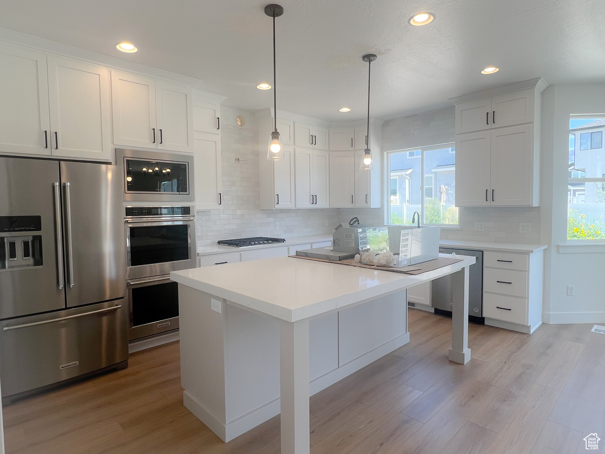 Kitchen featuring light hardwood / wood-style flooring, a center island, appliances with stainless steel finishes, and white cabinetry