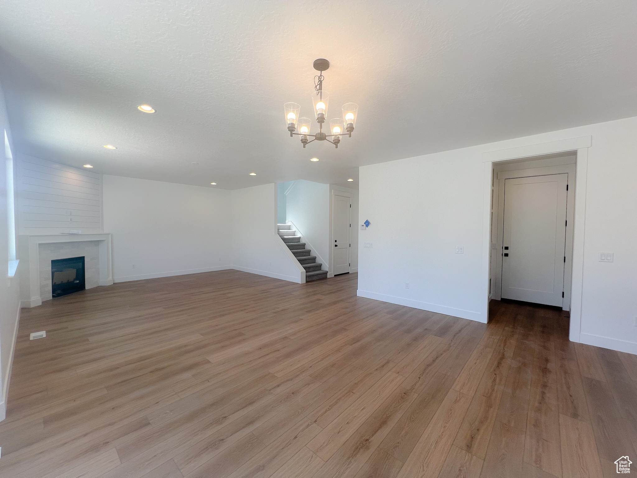 Unfurnished living room featuring a fireplace, a notable chandelier, and light hardwood / wood-style flooring