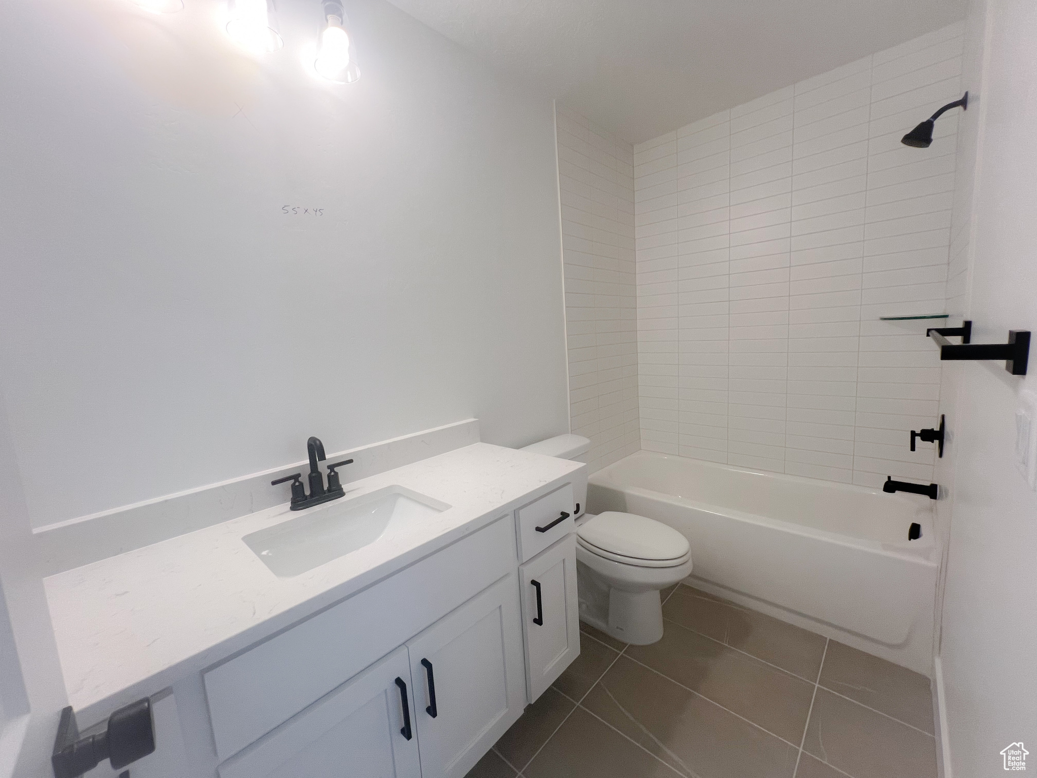 Full bathroom featuring vanity, toilet, tiled shower / bath combo, and tile patterned floors