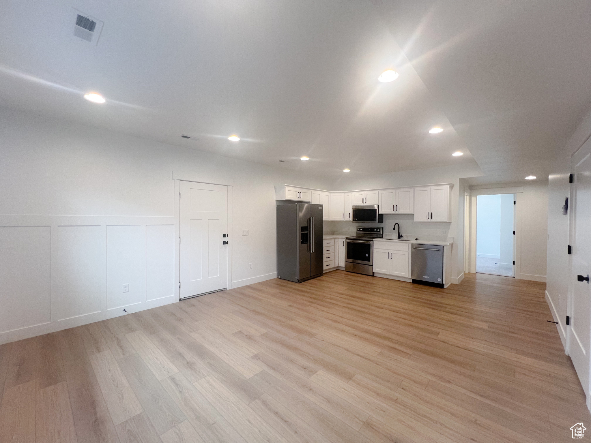 Unfurnished living room with sink and light hardwood / wood-style floors