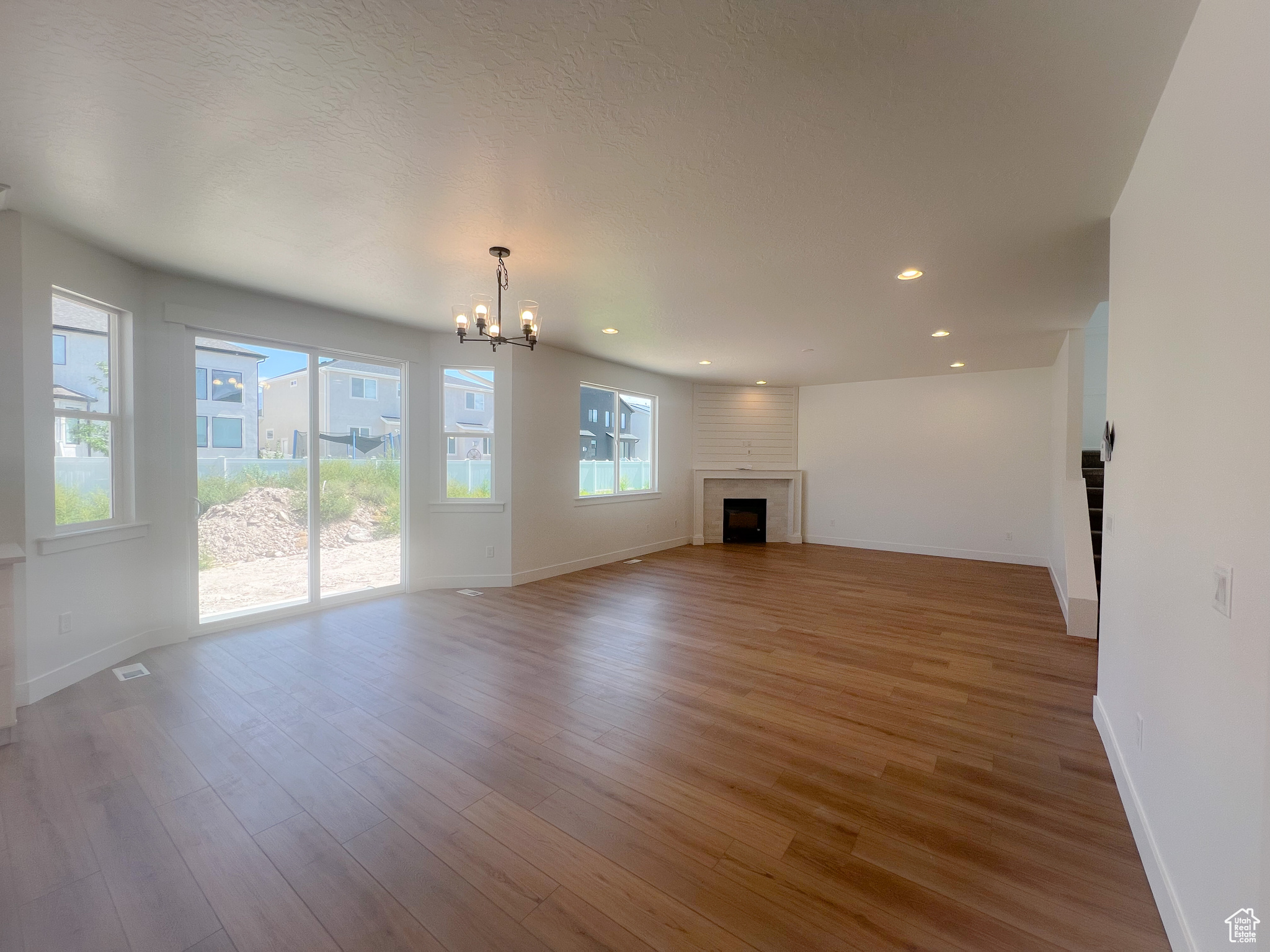 Unfurnished living room with a fireplace, a textured ceiling, wood-type flooring, and an inviting chandelier