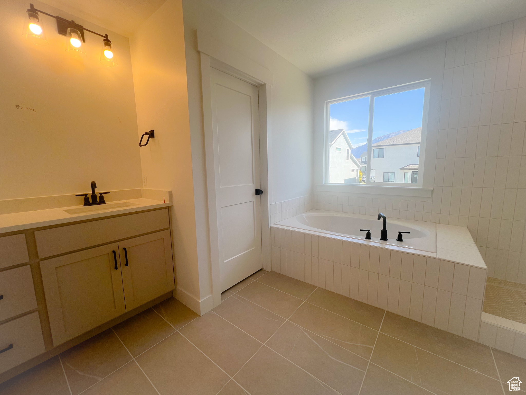 Bathroom featuring tiled tub, vanity, and tile patterned floors