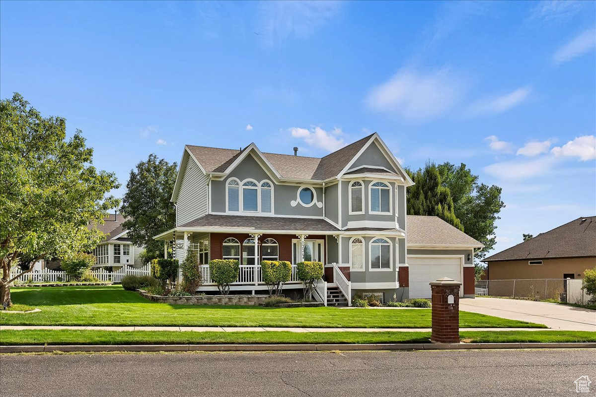 View of front of property featuring a garage, a front yard, and a porch