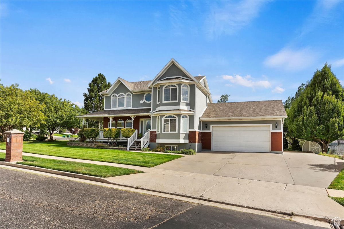 Victorian house featuring a garage, a front yard, and a porch