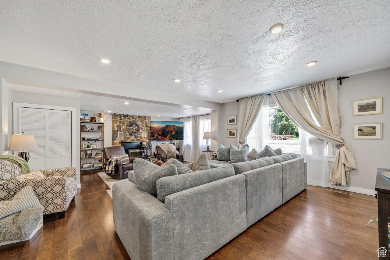 Living room featuring a fireplace, dark wood-type flooring, and a textured ceiling