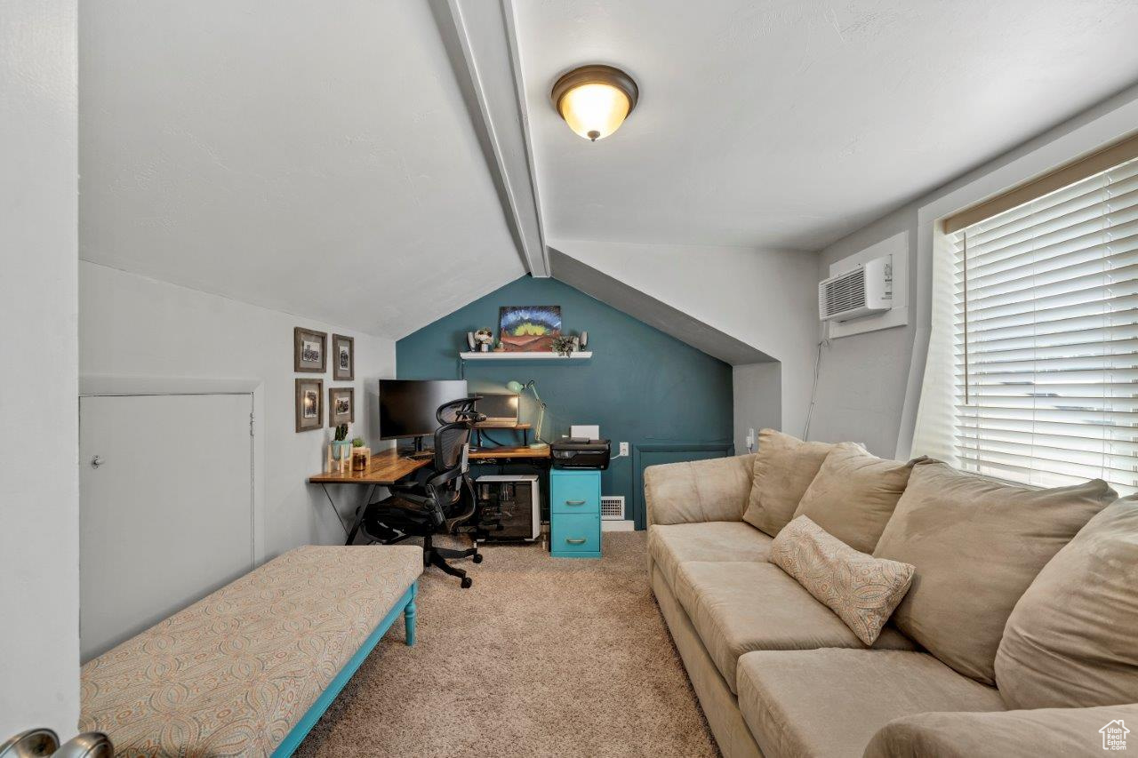 Carpeted home office with a wall mounted AC and vaulted ceiling